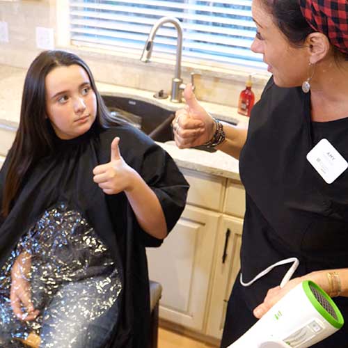 Technician giving thumbs up to child who is going to get treatment in her kitchen