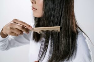 Close-up of a woman combing her long straight hair with a wooden comb.